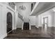Elegant two-story entryway featuring a dark hardwood floor, a grand staircase, and a crystal chandelier at 11091 Crooked Stick Ln, Carmel, IN 46032