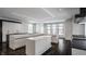 Modern kitchen with white cabinetry, large island, and dark hardwood floors at 11091 Crooked Stick Ln, Carmel, IN 46032