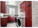 Laundry room with red cabinetry, granite countertops, and front-load washer/dryer at 11091 Crooked Stick Ln, Carmel, IN 46032