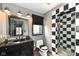 Modern bathroom with black and white tiled shower, dark vanity, and decorative mirror at 14990 E 104Th St, Fishers, IN 46040