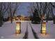 Winter scene of brick-columned driveway illuminated by lights leading to a beautiful home at 14990 E 104Th St, Fishers, IN 46040