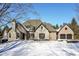 A snow covered house with a stone and brick facade, complimented by an attached garage at 14990 E 104Th St, Fishers, IN 46040