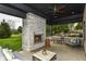 Covered patio with a stone fireplace, comfortable seating, and a view of the green lawn at 14990 E 104Th St, Fishers, IN 46040