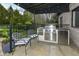 Outdoor kitchen area with stainless steel grill, mini fridge, and bar seating with chairs at 14990 E 104Th St, Fishers, IN 46040