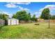 Backyard with a storage shed, fire pit, and a wooden fence, surrounded by green trees at 5327 Milhouse Rd, Indianapolis, IN 46221