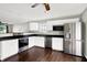 Modern kitchen featuring white cabinets, stainless steel appliances, dark countertops, and hardwood floors at 5327 Milhouse Rd, Indianapolis, IN 46221