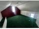 Attic bedroom with green carpet, two windows, and maroon accent wall at 1125 Laurel St, Indianapolis, IN 46203