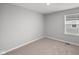 A cozy bedroom features neutral carpet, a window letting in natural light, and a fresh, simple aesthetic at 1713 Real St, Indianapolis, IN 46240