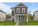 Charming two-story home with gray siding, white trim, a quaint porch and lush green lawn at 1713 Real St, Indianapolis, IN 46240