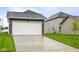 View of home featuring two-car garage, gray siding, and lush green front lawn at 1713 Real St, Indianapolis, IN 46240
