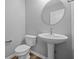 Clean and modern half-bath with pedestal sink, round mirror, and wood-look flooring at 1717 Real St, Indianapolis, IN 46240