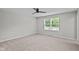 An empty bedroom features a ceiling fan, and neutral carpet with a well-lit window and minimal decor at 1721 Real St, Indianapolis, IN 46240