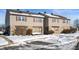 Tan siding duplex with stone accents, snowy front yard, and walkways at 2634 Country Estates Dr # 17, Indianapolis, IN 46227