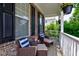 Relaxing front porch seating area with wicker chairs, blue pillows, and hanging flowers at 3460 Limelight Ln, Whitestown, IN 46075