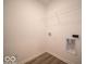 An efficient laundry room features white walls, gray wood-look flooring, a wire shelf, and hookups for a washer and dryer at 6636 Sulgrove Pl, Indianapolis, IN 46221