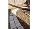 Landscaped backyard featuring a stone walkway leading to a deck, surrounded by grass and shrubbery at 704 S Ohio St, Sheridan, IN 46069