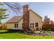 Rear exterior of home featuring a brick chimney, patio, and landscaped yard at 8104 Pocket Hollow Ct, Indianapolis, IN 46256
