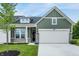 Charming exterior of a two-story home featuring green siding, a two-car garage, and a beautifully landscaped front yard at 9711 Palermo Ave, Indianapolis, IN 46239