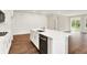 Stylish kitchen island with modern sink and dishwasher, set against white cabinets and wood-look flooring at 9711 Palermo Ave, Indianapolis, IN 46239