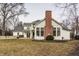 Rear view of a charming two-story house with a large brick chimney and expansive windows at 1303 Meadowbrook Dr, Indianapolis, IN 46240