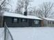 Gray house with black shutters, snowy yard, and chain link fence at 4715 E 33Rd St, Indianapolis, IN 46218