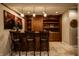 Finished basement bar featuring wooden bar stools, cabinets, and decorative lighting fixtures at 12596 Autumn Gate Way, Carmel, IN 46033
