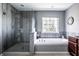 Modern bathroom featuring a glass enclosed shower, soaking tub, and grey-toned walls at 12596 Autumn Gate Way, Carmel, IN 46033