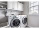 Functional laundry room featuring modern washer and dryer units, with storage cabinets and natural light at 12596 Autumn Gate Way, Carmel, IN 46033