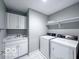 Well-lit laundry room featuring a sink, upper cabinets, shelf, washer, and dryer at 13650 Golden Ridge Ln, Fishers, IN 46055