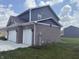 Gray home shows the brick side elevation, attached garage, and manicured lawn at 251 Dyson Dr, Whiteland, IN 46184