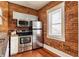 Compact kitchen featuring stainless steel appliances, brick accent wall, and practical layout at 643 Fort Wayne Ave # H, Indianapolis, IN 46204