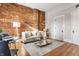 Inviting living space with exposed brick accent wall, hardwood floors, and neutral furnishings at 643 Fort Wayne Ave # H, Indianapolis, IN 46204