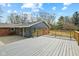 Wooden deck overlooking green yard with mature trees, next to a sunroom and patio at 8810 W Tulip Tree Dr, Muncie, IN 47304