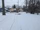 Snowy backyard with tire tracks and view of neighboring houses at 1128 N Holmes Ave, Indianapolis, IN 46222