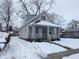 Tan house with white trim and porch, nestled on a snow-covered lot at 1128 N Holmes Ave, Indianapolis, IN 46222