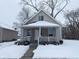 Tan house with white trim and porch, nestled on a snow-covered lot at 1128 N Holmes Ave, Indianapolis, IN 46222