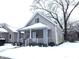 Tan house with white trim and porch, nestled on a snow-covered lot at 1128 N Holmes Ave, Indianapolis, IN 46222