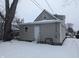 Rear view of house with beige siding, snowy yard, and visible AC unit at 1128 N Holmes Ave, Indianapolis, IN 46222