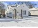 White house with a covered porch and snow covered yard at 1218 N Grant Ave, Indianapolis, IN 46201