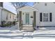 Quaint white house with teal door, covered porch and snowy yard at 1218 N Grant Ave, Indianapolis, IN 46201