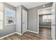 Gray-walled bedroom with wood-look floors, window, and door to another room at 1418 S New Jersey St, Indianapolis, IN 46225