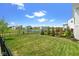 Expansive backyard with a lush lawn, landscaped garden, and community pond view from behind an iron fence at 15844 Nocturne Dr, Westfield, IN 46074