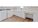 Bright laundry room featuring modern washer, dryer, white cabinetry, sink, countertop and wood grain flooring at 15844 Nocturne Dr, Westfield, IN 46074