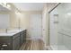 A bathroom featuring double sinks, quartz countertops, wood look floor, a white shower with glass doors at 1833 Luther St, Indianapolis, IN 46203