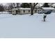 Ranch home with a snow covered yard and angel statue at 2515 Fairfax Rd, Indianapolis, IN 46227