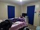 This bedroom features blue curtains, a television, and a bed with assorted bedding and personal items at 3951 N Pasadena St, Indianapolis, IN 46226