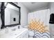 Bright bathroom showcasing a modern vanity, decorative mirror, and patterned shower curtain at 7129 Dublin Ln, Indianapolis, IN 46239