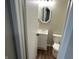 Cozy half bathroom featuring a toilet, vanity, updated mirror and wood-look flooring at 835 E Berwyn St, Indianapolis, IN 46203