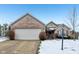 Brick ranch home with attached garage, landscaping, and snow-covered yard at 11537 Jagged Rock Ct, Fishers, IN 46037