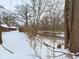 Snowy backyard with creek view, behind a rustic home at 2584 W Mercer Ln, Pendleton, IN 46064